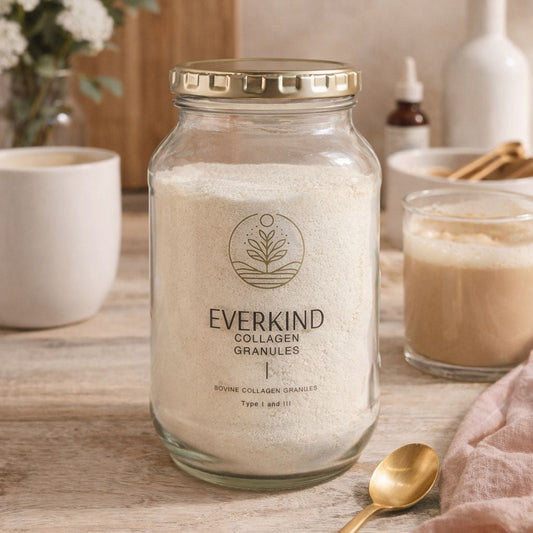 Glass jar of Everkind Collagen Granules on a wooden surface with a cup and spoon in the background.